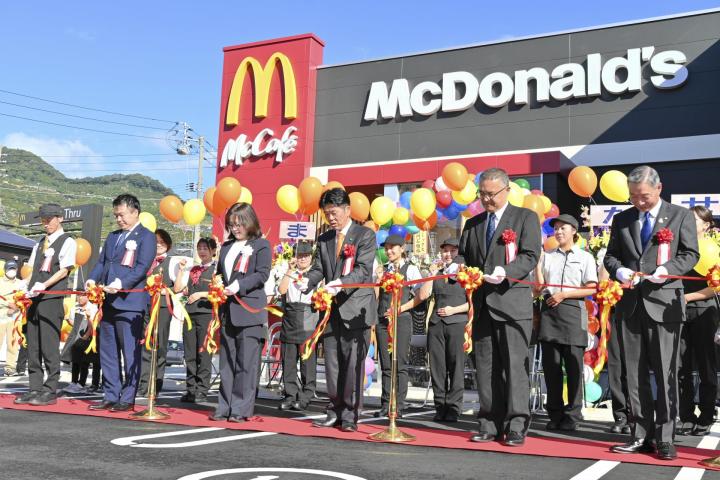 マクドナルド八幡浜店のオープンを記念し、はさみを入れる大石千枝社長（左から３番目）と大城一郎市長（右隣）ら＝１１日午前、八幡浜市昭和通