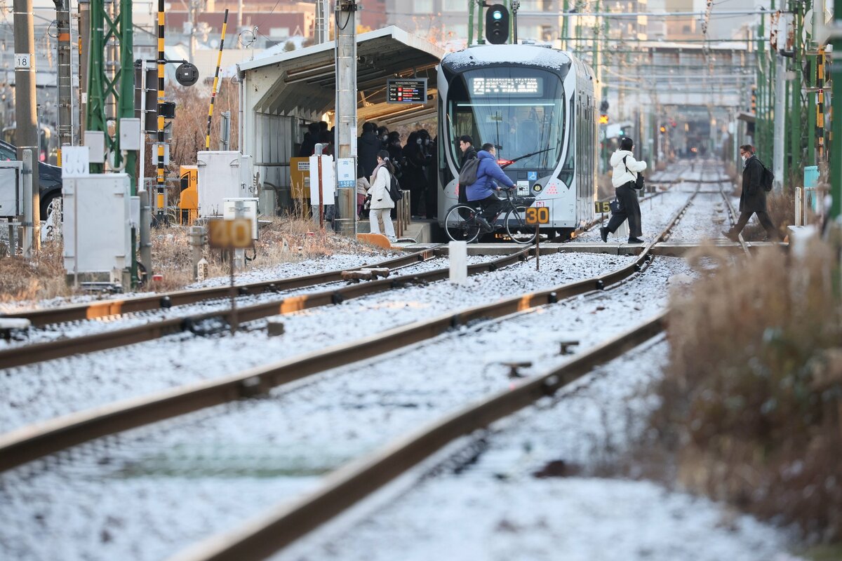 線路にもうっすらと雪が積もる中、職場などに向かう人たち＝５日午前７時42分、広島市西区（撮影・河田透）