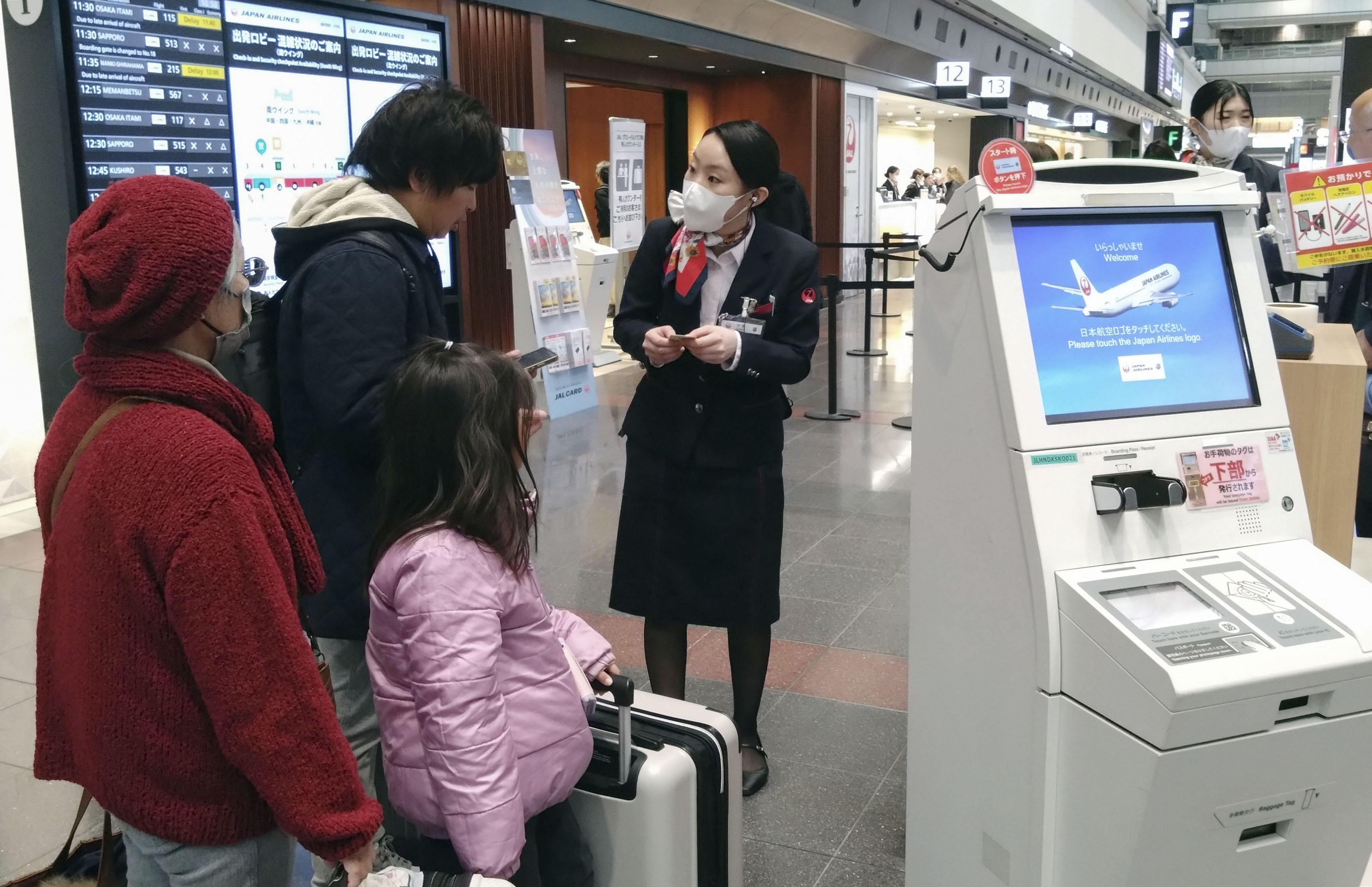 搭乗客の対応にあたる日航の地上職員＝26日午前、羽田空港