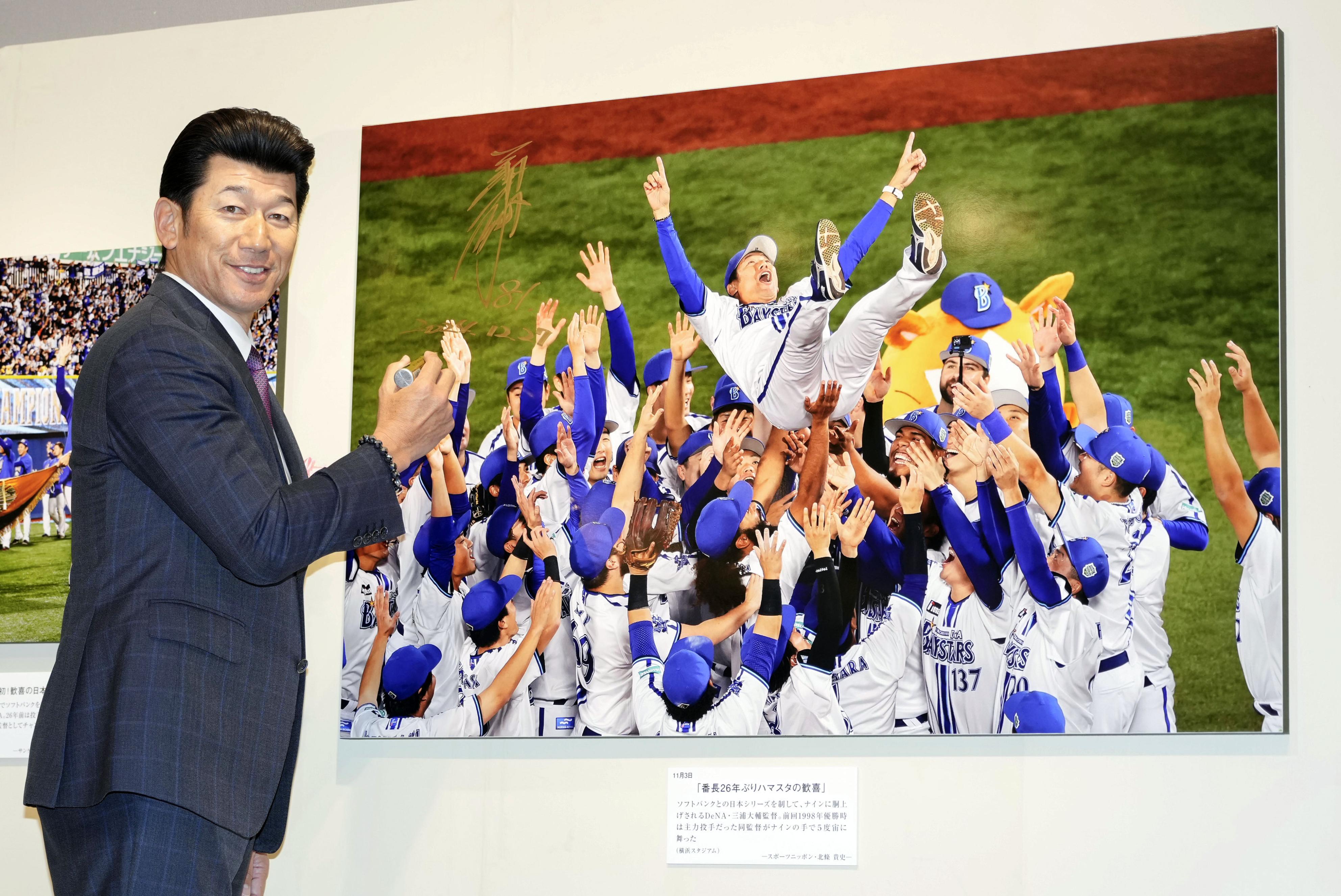 「2024年報道写真展」で自身の胴上げ写真にサインするDeNAの三浦監督＝27日午前、東京都中央区