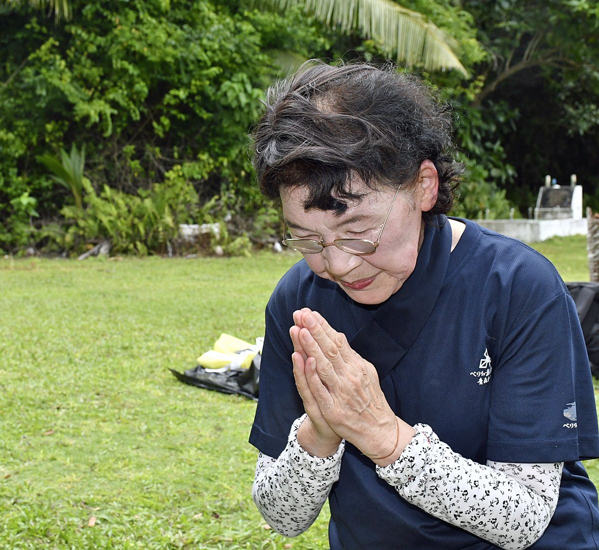 戦車隊の碑に手を合わせる田中さん＝13日午後2時45分ごろ、ペリリュー島