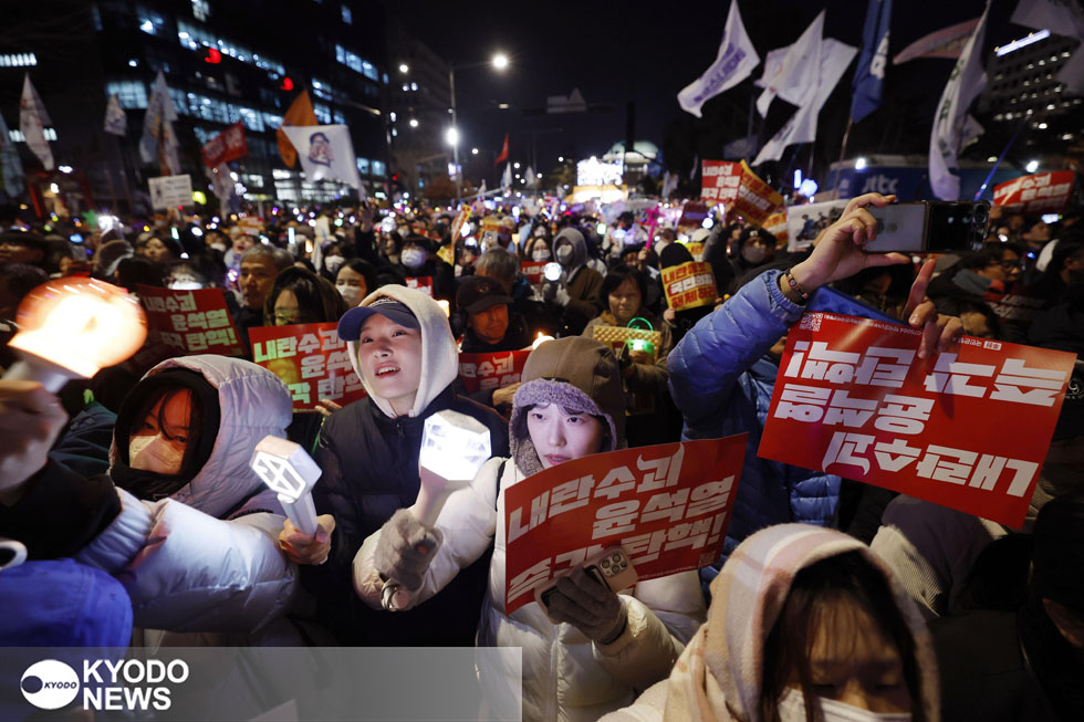 韓国・ソウルの国会周辺で、プラカードを手に尹錫悦大統領の弾劾を求めてデモ行進する人たち＝２０２４年１２月９日（共同）