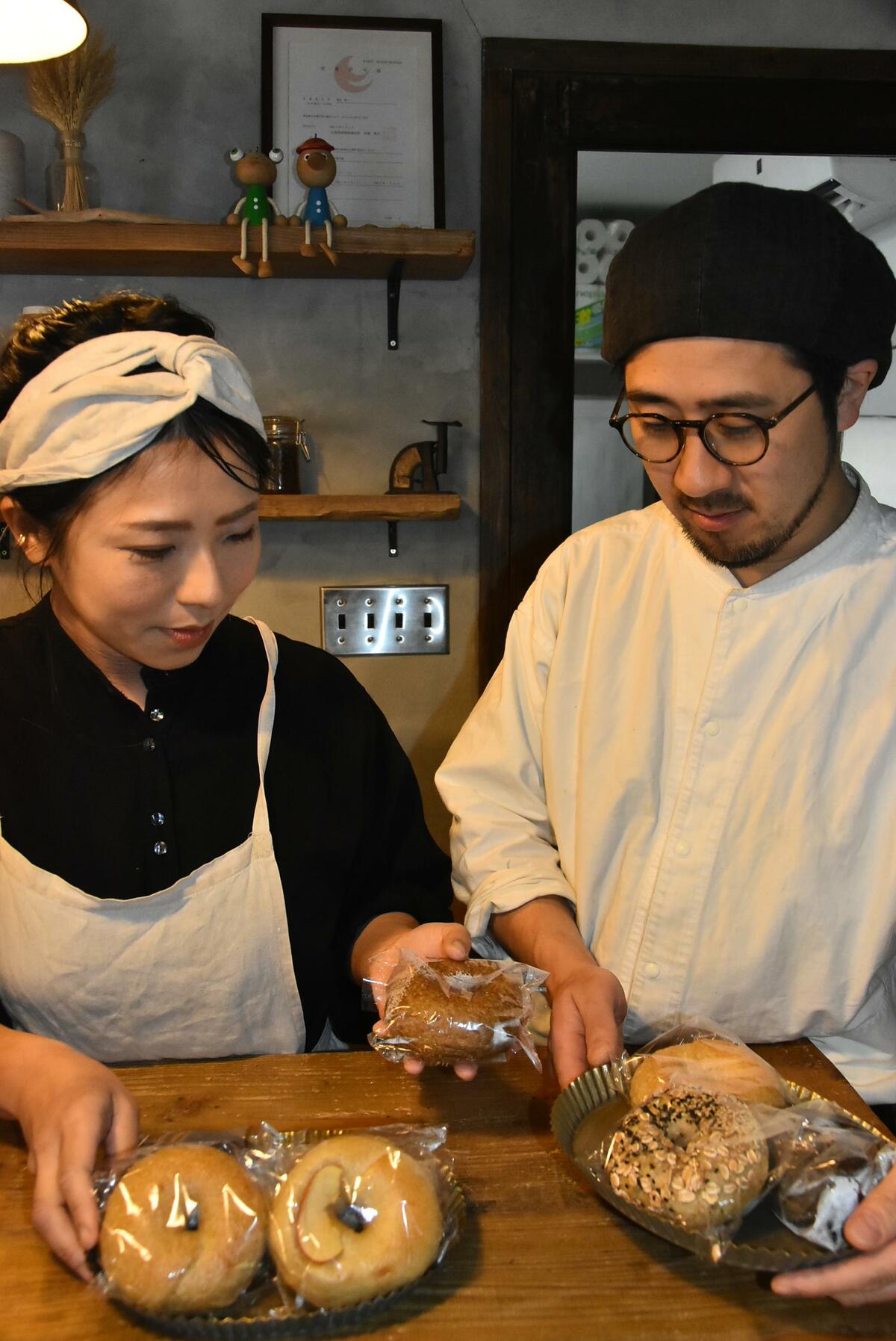 出来たてのベーグルをチェックする裕一さん㊨と沙織さん