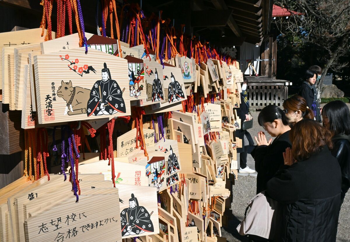 ずらりと並んだ絵馬の前で学業成就の願をかける家族連れ＝13日午前10時50分、芳賀町西水沼