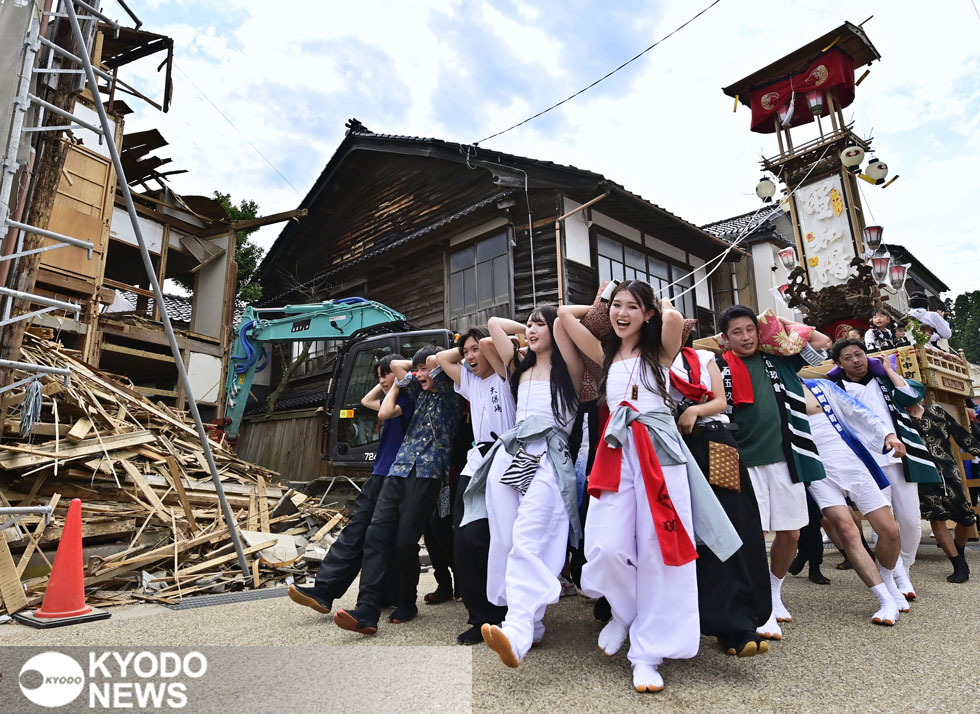 石川県能登町のあばれ祭で、キリコを担いで歩く町民ら。家屋の解体が進む中、「イヤサカヤッサイ！」のかけ声が響いた＝２０２４年７月５日（共同）