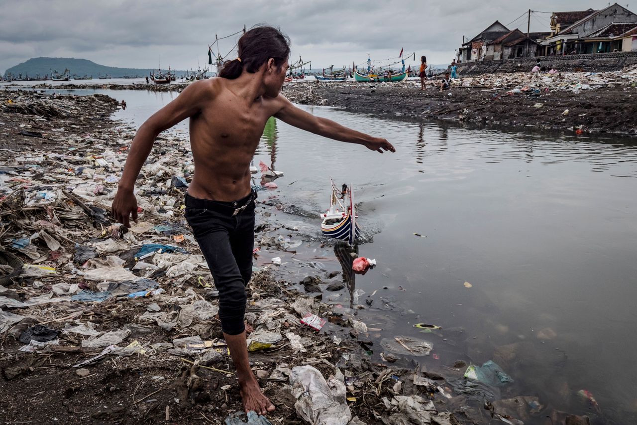 Children playing amid plastic waste at Muncar port.