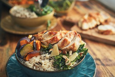 Chicken rice bowl on wooden table, a meal that incorporates lean proteins to help lose weight safely