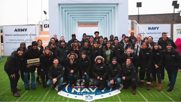 A large group photo of military veterans in matching shirts at a conference.