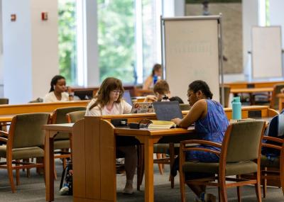 Students seated at desks working on laptops and studying