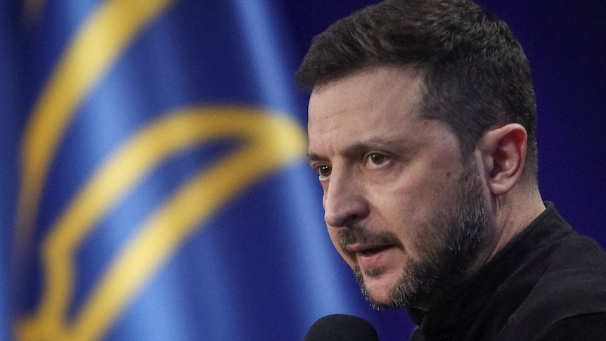 Volodymyr Zelenskyy at a press conference speaking into a microphone