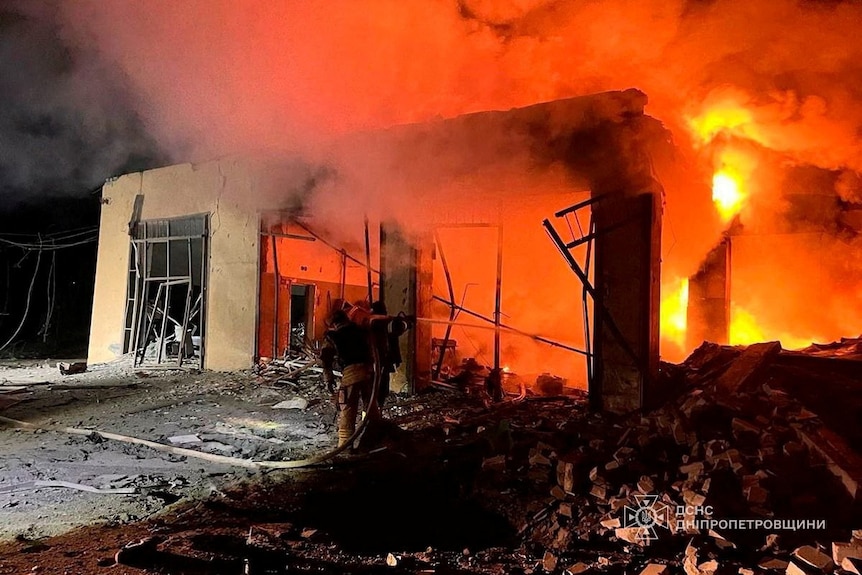 A fire burning in a bombed-out building at night.