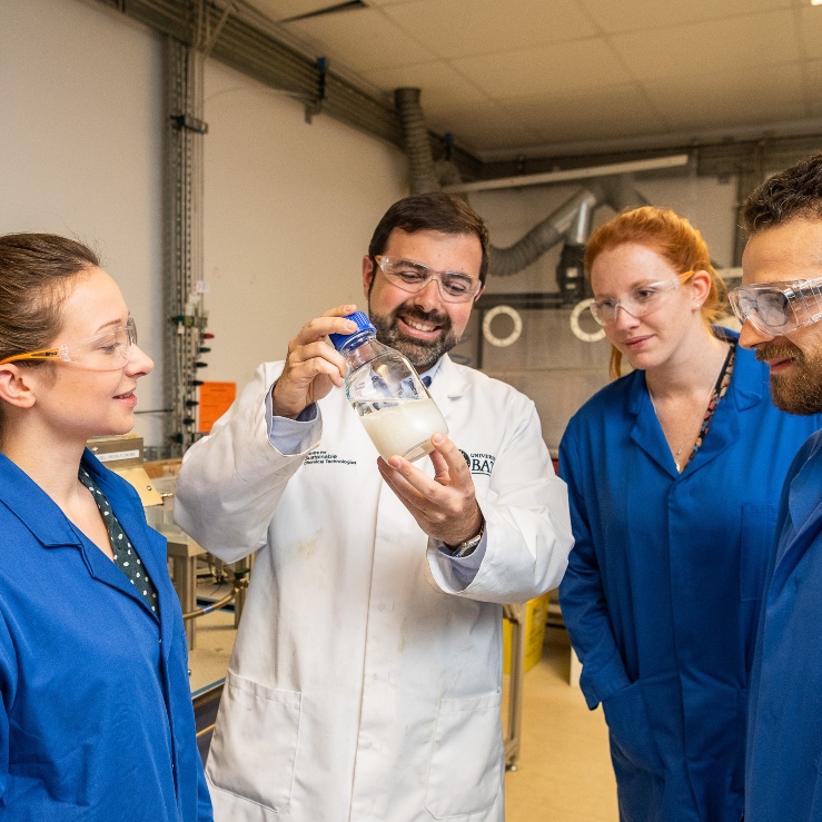 A Bath researcher shows a flask of liquid to a commercial business partner