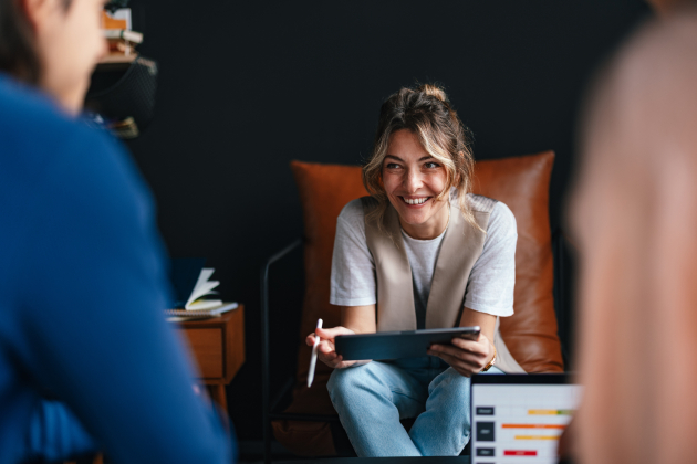 Portrait of a beautiful woman sitting in a chair using a digital tablet and looking away