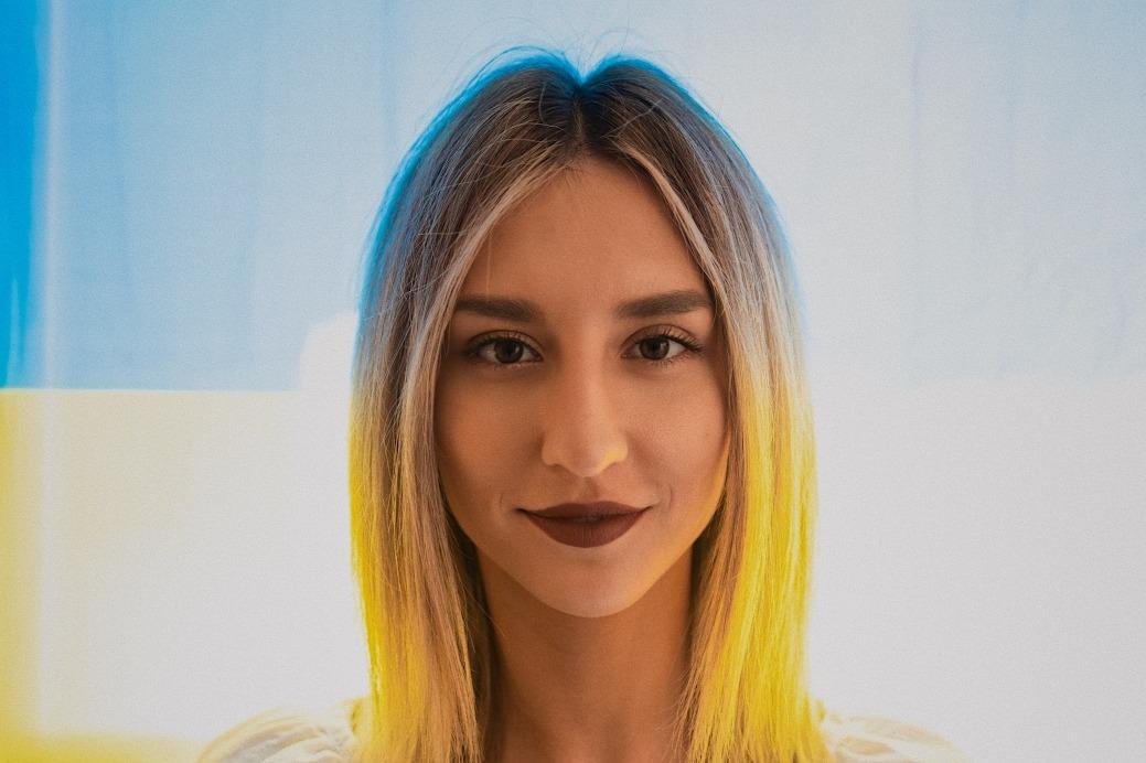 Tetiana Tytko poses for a headshot in front of the Ukrainian flag.