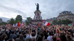 TOPSHOT - Participants wave French national tricolours during an election night rally following the first results of the second round of France&apos;s legislative election at Place de la Republique in Paris on July 7, 2024. A loose alliance of French left-wing parties thrown together for snap elections was on course to become the biggest parliamentary bloc and beat the far right, according to shock projected results. (Photo by Emmanuel Dunand / AFP) (Photo by EMMANUEL DUNAND/AFP via Getty Images)