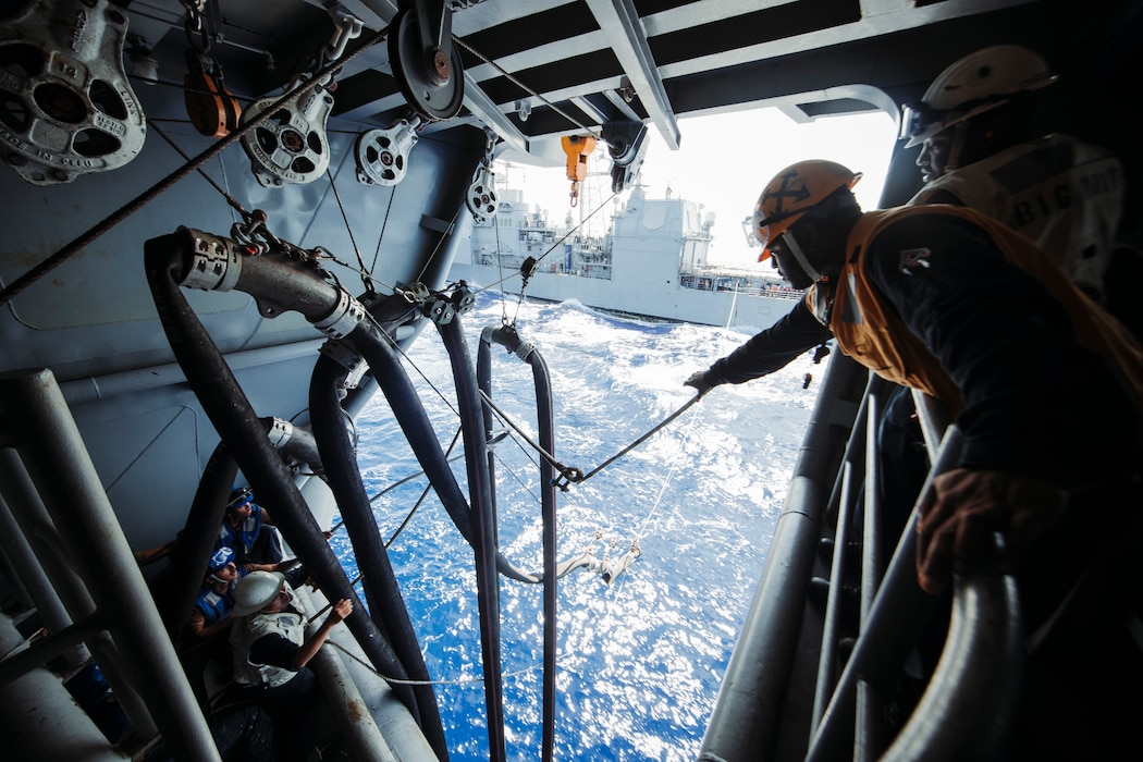 Sailors adjust a fuel hose at a fueling station aboard USS George Washington (CVN 73) during a fueling-at-sea with USS Shiloh (CG 67) in the Pacific Ocean.