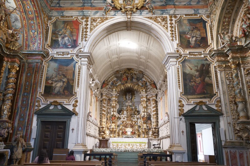 The main altar of a gilded church, flanked by four paintings.