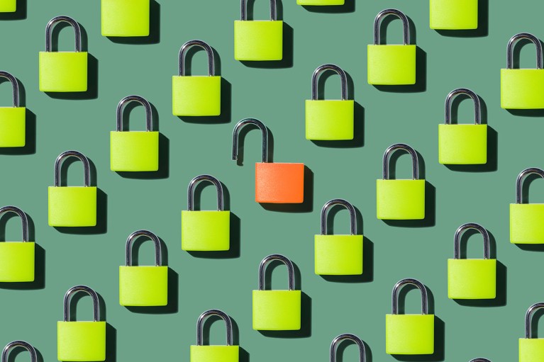A single open orange colored padlock surrounded by many locked green colored padlocks.