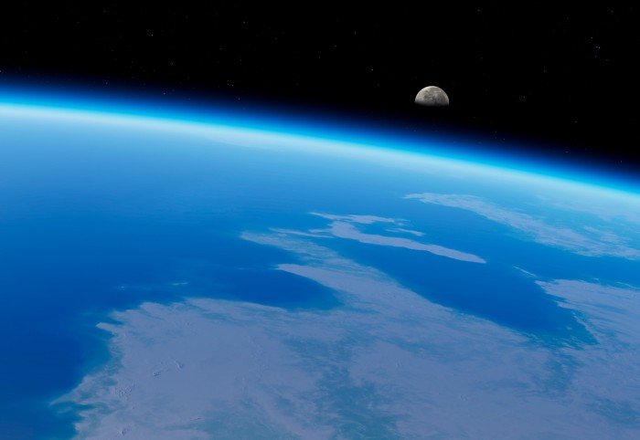 A view across the Earth's outer atmosphere with the moon rising on the horizon on the right hand side