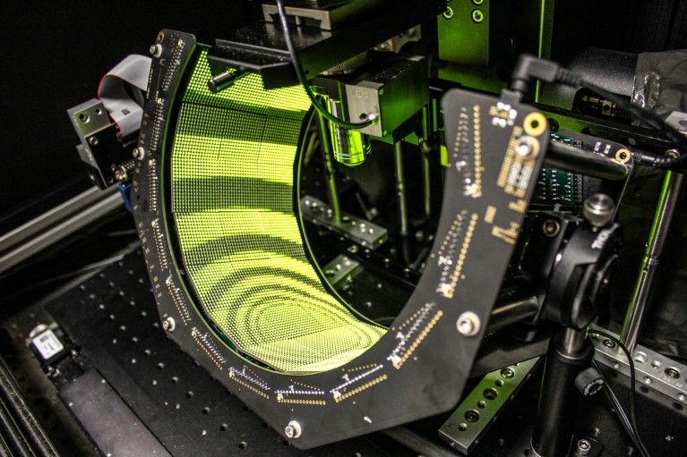 A semi-circular light display under a microscope showing visual patterns used to create a virtual arena for a fly