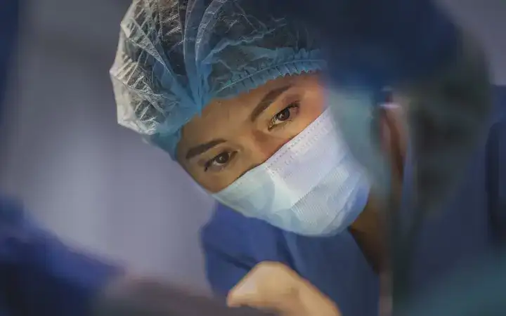 Female surgeon looking at a patient in a hospital operating theatre