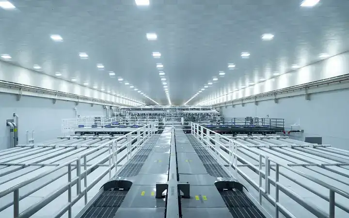 A massive white room with long pipes and walkways extending as far as the eye can see.