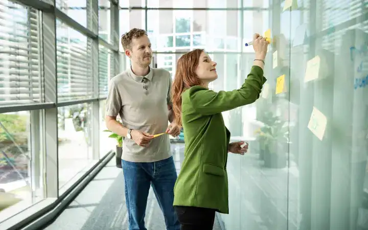 Women and Man standing on a whiteboard