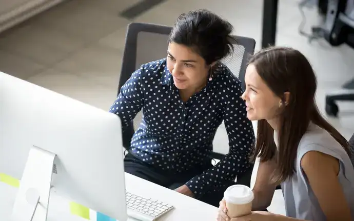 Two young people looking at a monitor in an office