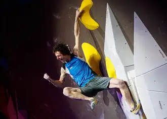 Man punches the air while climbing a boulder wall 