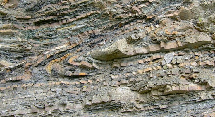 A cliff with different colour rock layers running horizontally.