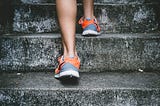 pair of legs wearing shoes taking steps up concrete stairs