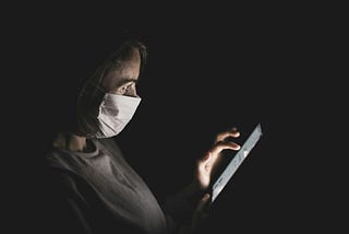 A masked woman using an iPad