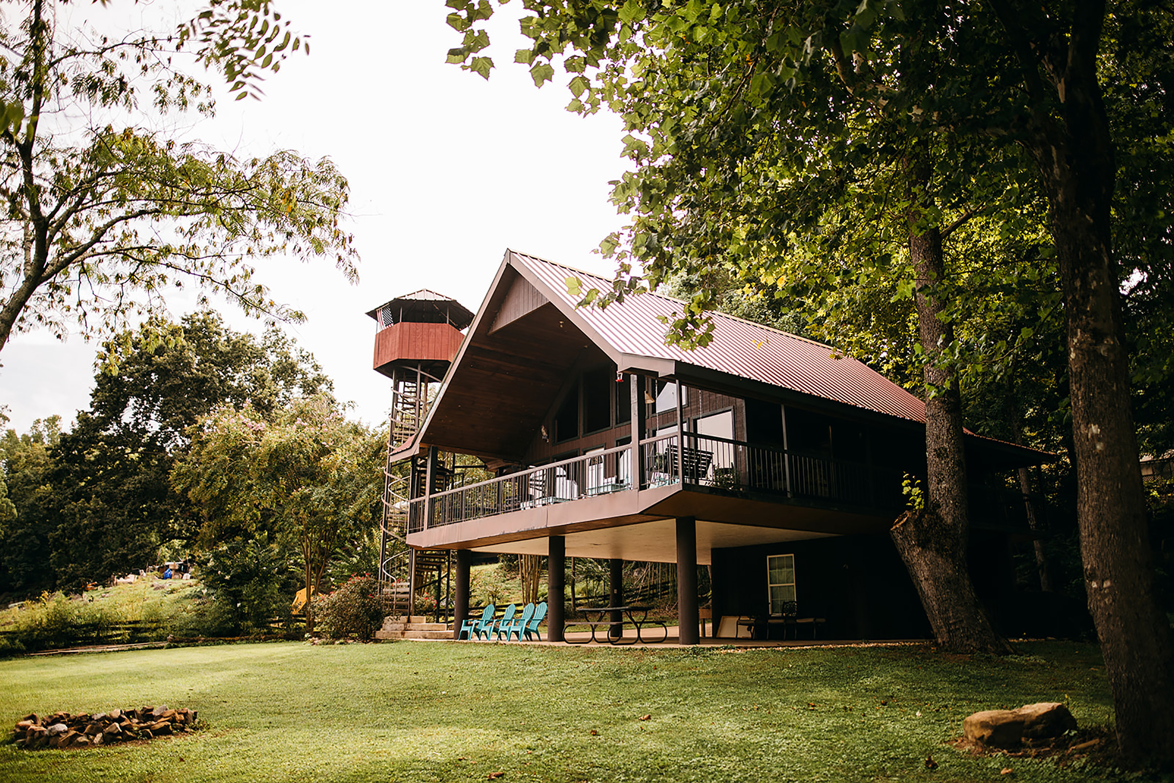 Industrial looking farmhouse and treehouse hybrid with a silo alongside it.