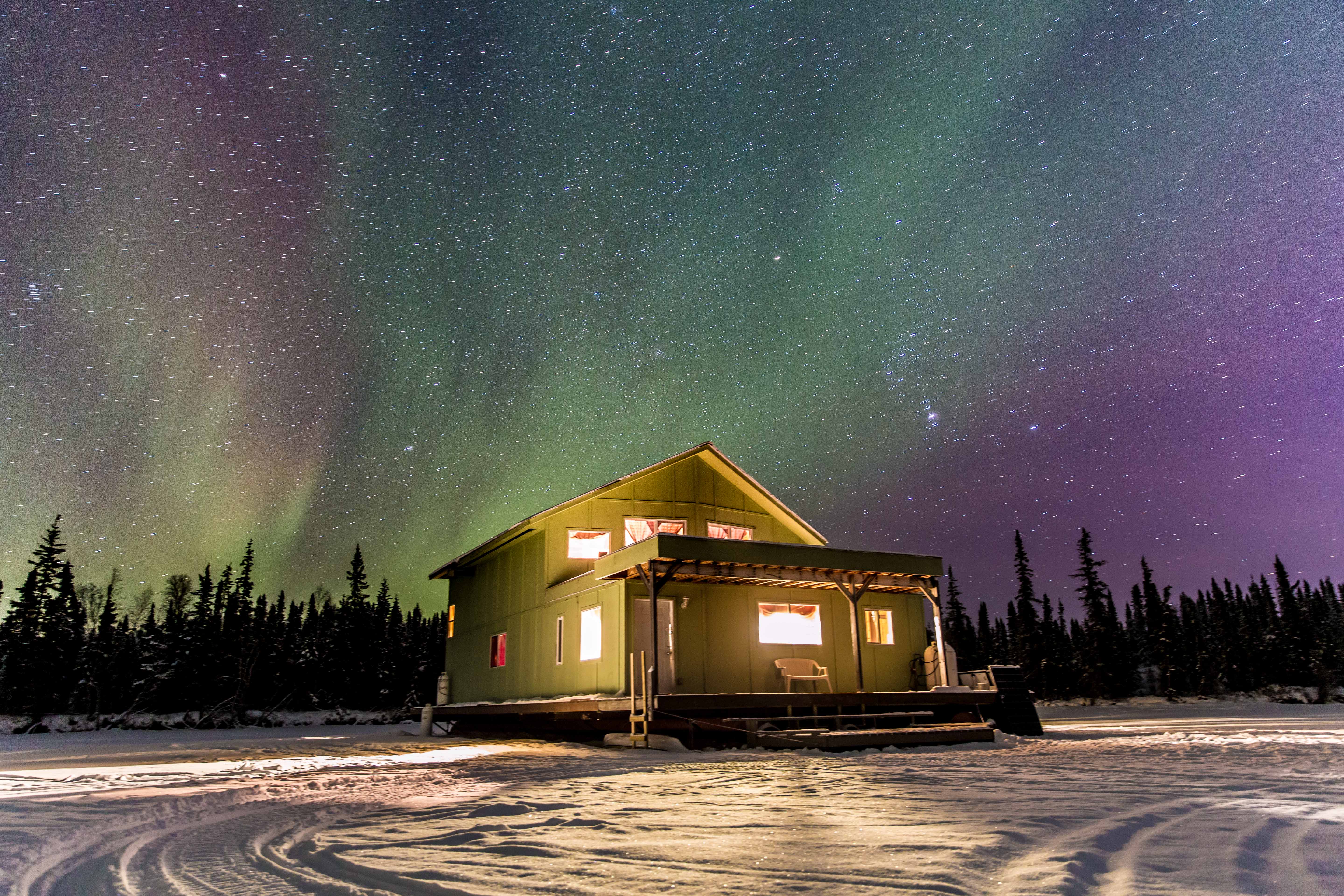 A northern Canadian cabin basking in the northern lights.