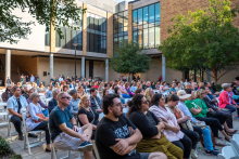 Rows of people seated in the Art Building Courtyard in white chairs for CVAD Celebrates!