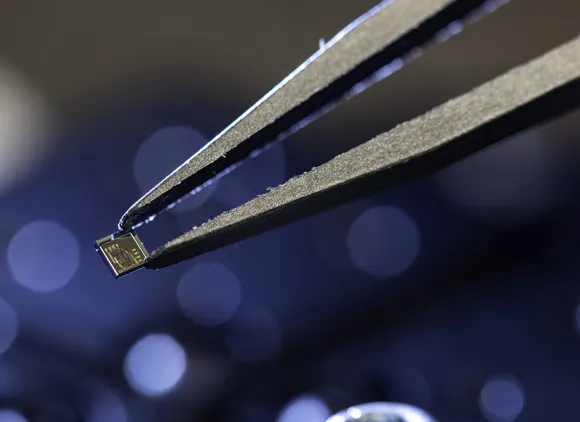 Closeup of tweezers holding a tiny chip.