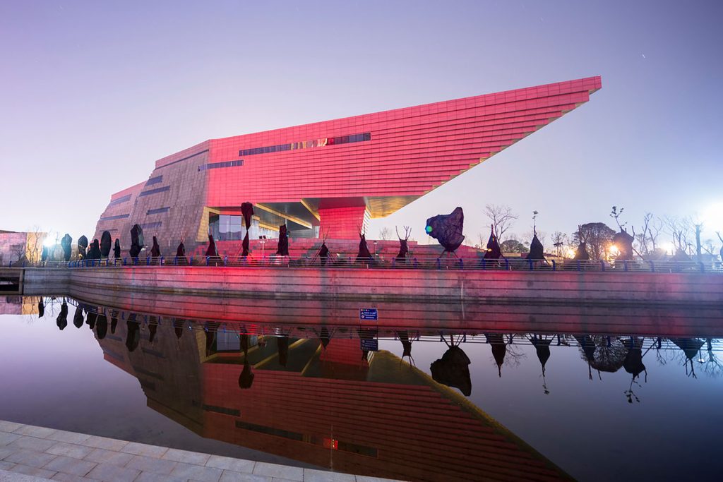 The Qujing Culture Center at dusk, illuminated with warm lights, inviting visitors inside.