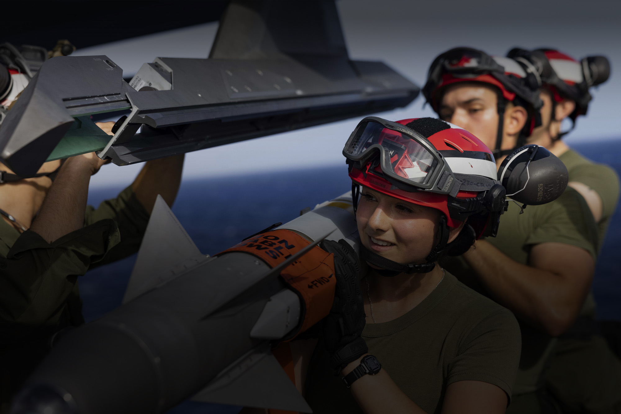 4 soldiers loading ammunition on a fighter jet