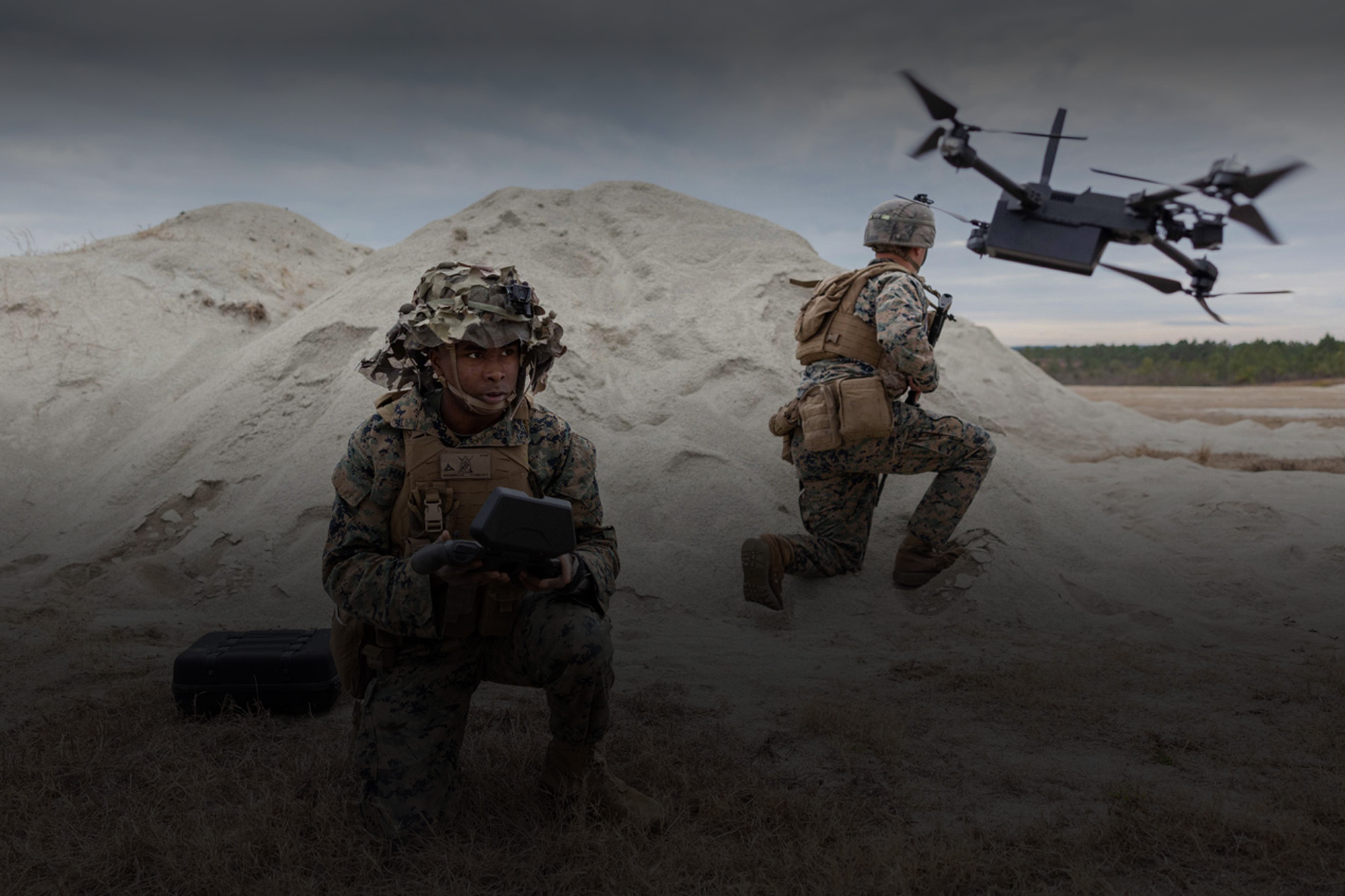 Two soldiers flying a drone on a beach