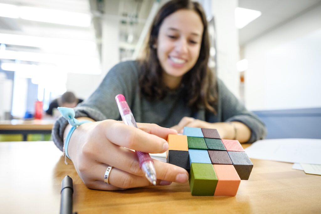 A smiling student is trying to figure out a puzzle.