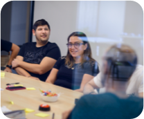 Several colleagues in a meeting room enjoying a relaxed work conversation.