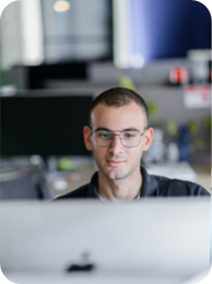 A member of the team looking into their working screen with the office space blurred out in the background.