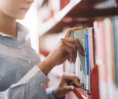 Woman looking for a book on a library shelf