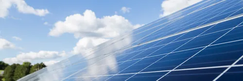 Solar panels on a roof surrounded by a sunny sky.