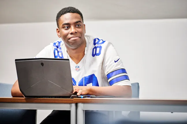 Students smiling while using a laptop