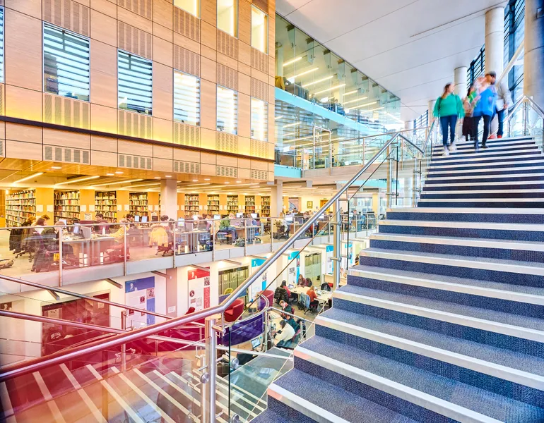 Students walking down the staircase into the library