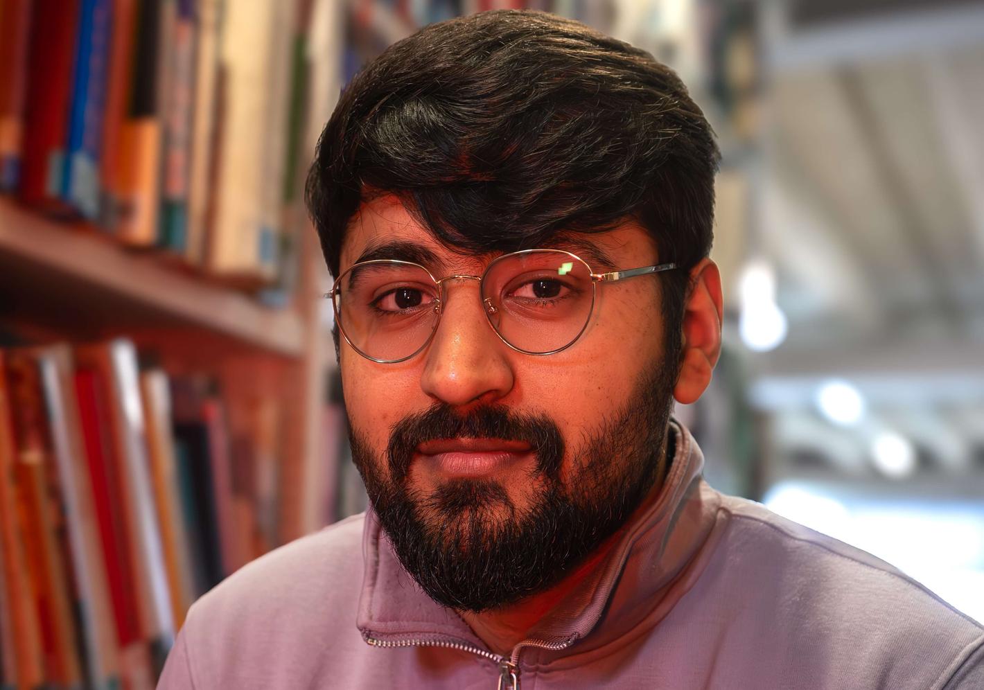 Student sitting in library with books behind