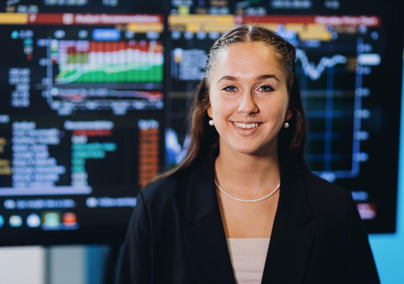 student stands in front of finance display