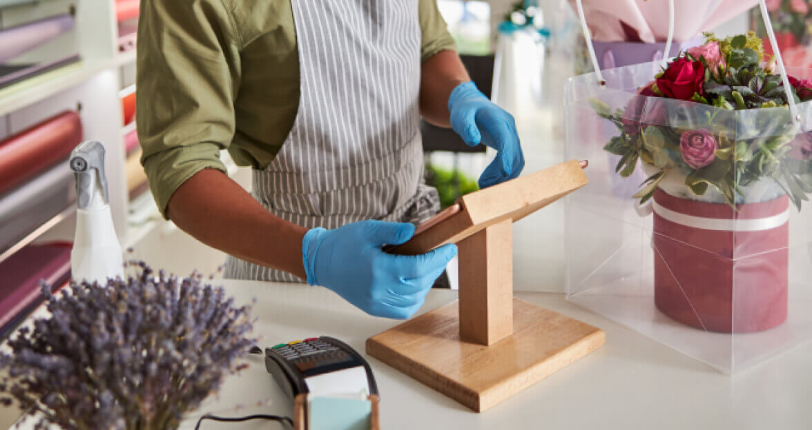 Floral shop checkout counter with a worker entering info into a tablet.