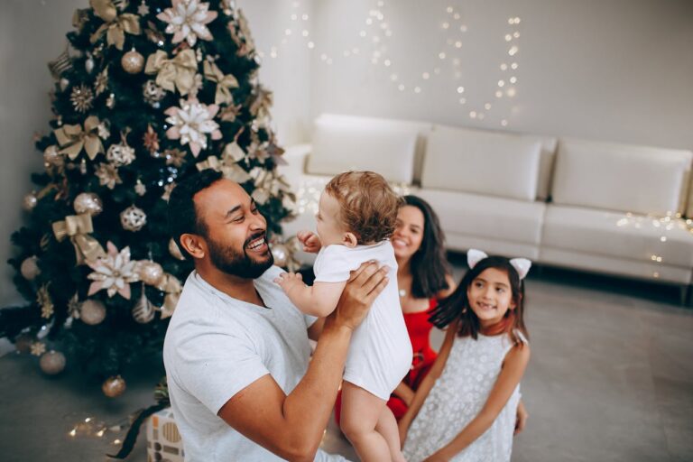 Father picking up toddler while other family members watch.